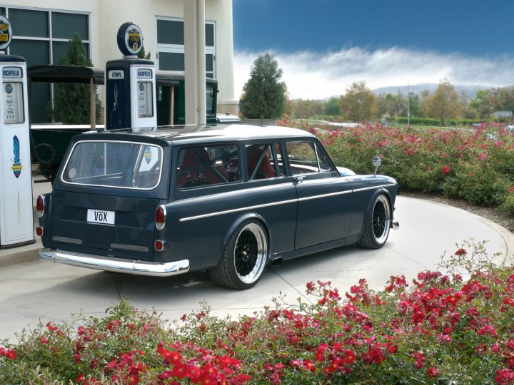 Modified Decently Pistonheads - The image captures a classic blue car positioned in the foreground of the frame. It's an antique model, characterized by its old-fashioned charm. The car, with its round body and a spare tire mounted on the back, is parked in a gas station parking lot. The lot is lined with oxpecker and gooseberry bushes, adding a touch of nature to the otherwise man-made environment. Further in the background, a gas pump can be seen, completing the scene of this historic car in a vintage setting. The image conveys a sense of nostalgia, with the classic car representing a bygone era.