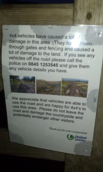 Pistonheads Horwich Bolton Georges Lane - The image displays a signboard with a message attached to a wooden fence or support post. The sign conveys that you have entered a lot at your own risk and directs attention to 4x4 vehicles moving through or parked in the area. It also mentions certain circumstances and requests that visitors pay attention and be cooperative in the area. The signboard is sage in color, and its text is clear and legible. The surroundings suggest this could be a boating or off-road area due to the emphasis on 4x4 vehicles.