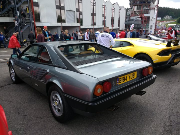 Road trip in a 70's or 80's Ferrari? Bad idea? - Page 2 - Ferrari Classics - PistonHeads UK - The image showcases a gathering of vintage cars at an outdoor event. Dominating the scene is a silver sports car, its sleek design and shiny exterior reflecting under the open sky. This car appears to be in good condition, possibly recently restored or maintained, given its pristine appearance. 

In the background, other classic vehicles can be seen, each with their own unique designs and colors. These cars are parked haphazardly, suggesting a casual and relaxed atmosphere at this event. A few people can also be spotted in the distance, adding a lively touch to the scene. 

The presence of multiple sports cars indicates that this event is likely focused on automotive enthusiasts who appreciate classic vehicles. The open sky and outdoor setting suggest a pleasant day for such an event. Overall, the image captures the vibrant energy of a car show dedicated to vintage models.