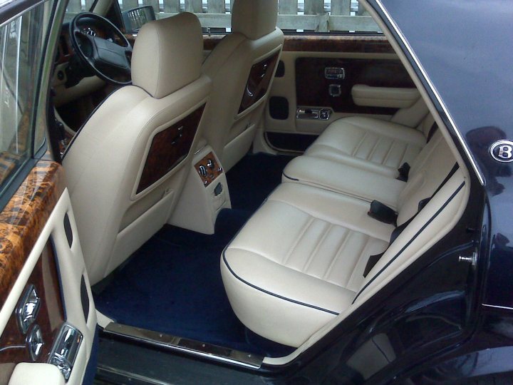 Turbo Pistonheads - The image shows the interior of a luxury car, viewed from the perspective of standing outside. The focus is on the interior, likely taken by an owner or enthusiast. The car appears to be fitted with high-quality leather upholstery, with precise stitching, and the seats are designed for comfort. The dashboard features an array of gauges and controls, suggesting the car has advanced technology. The dark exterior of the car provides a contrast to the lighter tones of the car's interior.