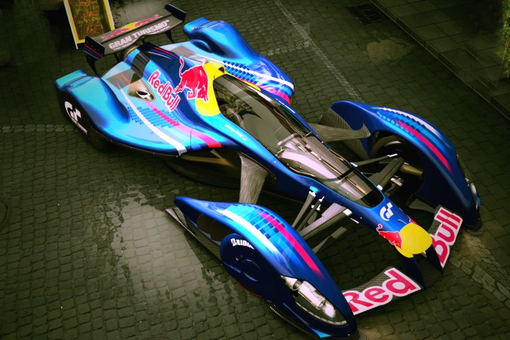 A person riding a motorcycle on a track - Pistonheads - The image features a concept car that closely resembles the design language of Red Bull. The car is predominantly blue with accents of yellow and red, reflecting the colors of the Red Bull brand. Its aerodynamic shape and multiple air vents suggest optimized wind resistance. The image is set in a dark garage, allowing the car's vibrant colors to stand out. The car's design is striking and modern, evoking a sense of luxury and speed.