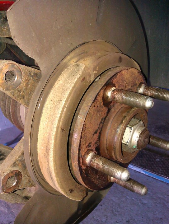 Pistonheads - The image shows a close-up of an automotive component, specifically what appears to be a vehicle's suspension or damping system. It features a metallic structure with several bolts, suggesting it is part of a larger assembly within the vehicle. The component is viewed from a low angle, looking up and to the left, and the image is taken outdoors during the day, as indicated by the lighting and shadows. The photo is taken in color, which enhances the textural details of the metal. The focus is sharp, allowing for a detailed examination of the various parts of the system, such as the joints and the threading on the bolts.