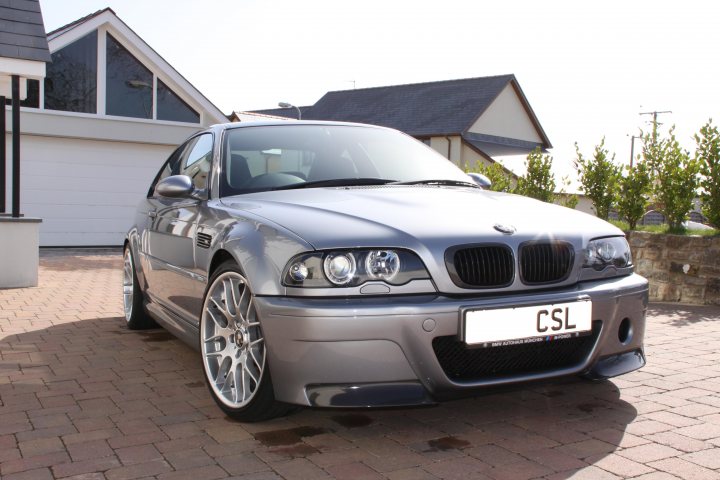 Clean Pistonheads Spring - The image features a silver car parked on a brick driveway. The car is a Eurospec BMW model, identifiable by its distinctive front grille and unique badges. It has alloy wheels and a European-style front plate. The driveway is bordered by a paved pathway that leads to a house that's partially visible in the background. The overall setting suggests a residential neighborhood on a day with clear weather. The image also contains a watermark that reads "CSL," indicating it might be associated with a car dealership or similar service.