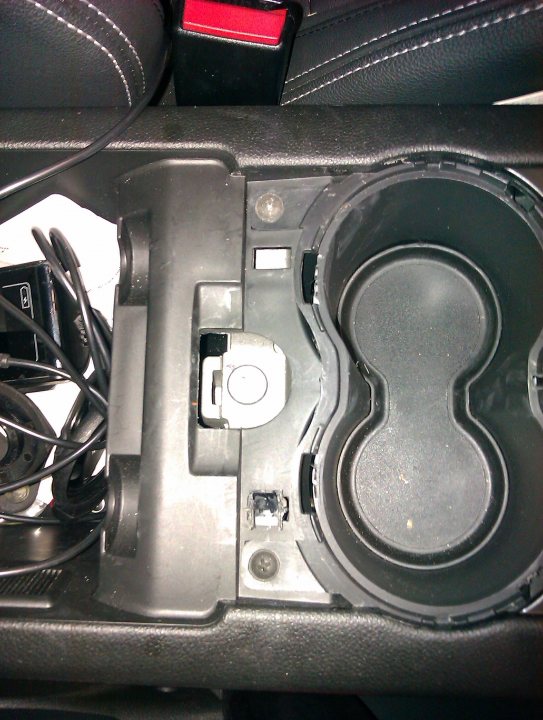 Pistonheads - The image provides a close-up view inside a vehicle's storage compartment, showing a variety of stored items. The compartment features an open lid and is lined with a dark interior, possibly to protect the contents. Inside, there's a notable presence of cables and electronic devices such as an Apple product, suggesting that the owner might be involved in technology or entertainment. The design of the compartment suggests it's designed for easy access to these items, indicating it might be used as a storage space for important items. The silhouette of the space plays a role in holding the user's attention to the items stored within its confines.