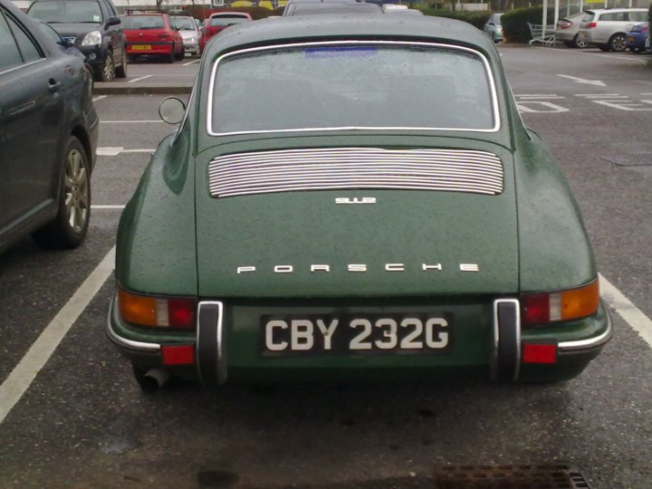 COOL CLASSIC CAR SPOTTERS POST!!! - Page 215 - Classic Cars and Yesterday's Heroes - PistonHeads - The image features a vibrant green Porsche car parked in a lot. The car is focused on from a low angle, emphasizing its curved lines and prominent badge. The vehicle's license plate stands out against the green paint, indicating the car's readiness for the road ahead. In the background, other cars and a parking lot are visible, providing context and a sense of location.