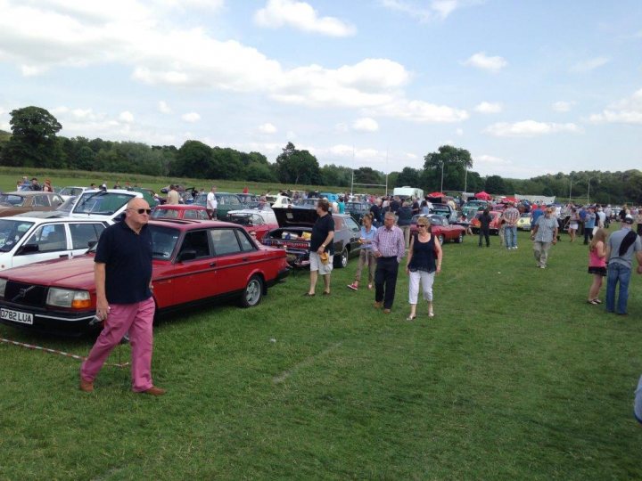 Corbridge classic show - Page 1 - North East - PistonHeads - The image shows a parking lot filled with vintage cars, from the mid-20th century. A large crowd of people is spread across the field, walking around and looking at the cars. The ground is covered in grass, hinting at a relaxed and informal setting. The perspective of the image is from the perspective of someone walking amidst the cars and people. The day appears to be slightly overcast, but the overall atmosphere is lively and enjoyable.