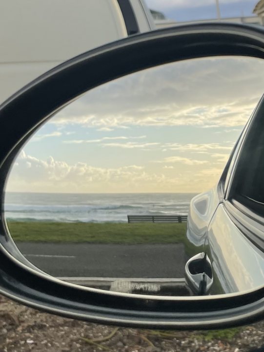 A rear view mirror of a car driving down a street - Pistonheads