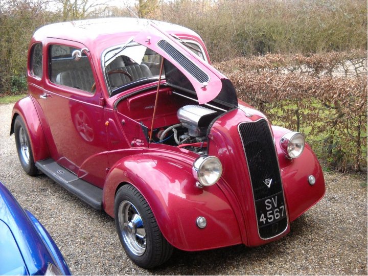 Lets see a picture of your classic(s) - Page 86 - Classic Cars and Yesterday's Heroes - PistonHeads - The image depicts a striking red vintage car parked on a gravel driveway. The car features a pink hood with a large V-shaped grille, which is a notable characteristic of the vehicle. The vehicle has round headlights, and the hood is propped open, revealing the engine under the open pink hood. The rear of the car is visible, showing the emblem and licence plate with the letters "SV". The car exudes an air of antiquity and seems to be carefully maintained.