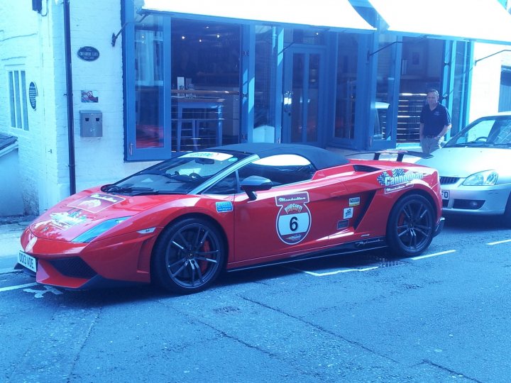 The BAD PARKING thread [vol3] - Page 45 - General Gassing - PistonHeads - The image shows a vibrant red sports car parked on a city street. The car is sleek and appears to be a newer model. Parked next to the sports car is a silver car, which is considerably less striking in comparison. The building in the background has blue-trimmed windows, giving a fresh vibe to the setting. On the sidewalk, there's a black metal barrier, adding a touch of urban design to the scene. A pedestrian is visible, adding a sense of scale and life to the image.