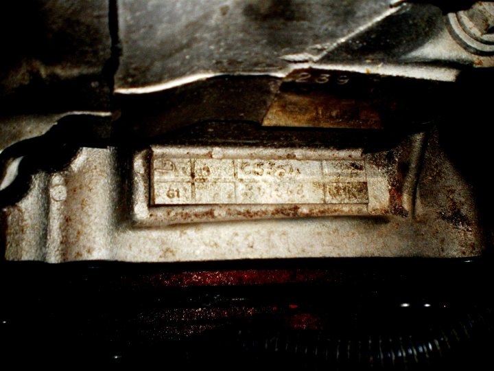 How do you make a 3 door Cosworth go fast????????? - Page 1 - Vipers - PistonHeads - The image is a close-up, primarily in black and white. It shows a mechanical component, possibly an engine or a metal part with a slightly corroded contact point or area with text. This text is not entirely legible but appears to include characters that could be a model number or serial code. On one side, there is a blurred wire or possibly a black object with several metal projections or contacts. The overall condition of the object suggests wear and it appears aged or used, perhaps throughout a mechanical system.