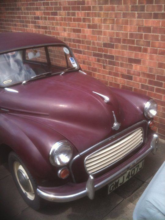 1971 Morris Minor 1000 Resto thread (Maybe) - Page 1 - Classic Cars and Yesterday's Heroes - PistonHeads - The image captures an older model car, parked against a brick wall. The car features a vibrant purple or maroon body with a shiny metallic bumper and a round side view mirror. It has a classic design, with no visible modern enhancements, and the colors contrast with the reddish-brown of the brick wall behind it. The car's vintage style suggests historical significance or the owner's affinity for classic vehicles. The license plate is clearly visible, indicating the location of the vehicle.