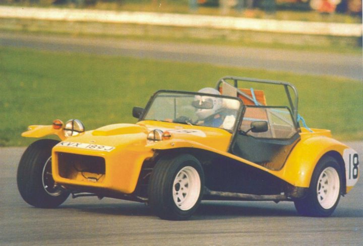 Lotus 7 - S4 - Page 5 - Caterham - PistonHeads - The image displays a person driving a vintage yellow sports car on a road. The car is eye-catching with its bright color and sleek design, featuring a large rounded front, narrowing towards the rear. The driver appears focused on the open road ahead. The setting is an open-air road surrounded by grass, indicating an outdoor driving area. The car's license plate prominently reads "R50," suggesting it's a registered vehicle. The style of the image suggests it might be an old photograph, capturing the essence of classic sports car driving.