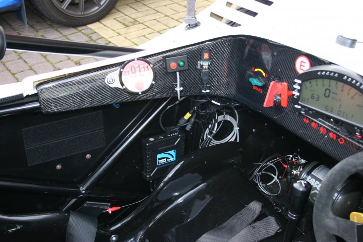 Ride Road Pistonheads - The image shows the interior of a car, focusing on the control panel situated in the center console. The panel is predominantly black with various switches and dials, suggesting a high-tech or high-performance vehicle. It includes a digital display screen and circular gauges, which are typical features of racing or performance cars. The panel appears to be designed for functionality and control, and it occupies a substantial part of the dashboard area. The image is a close-up photograph, emphasizing the details of the panel's components.