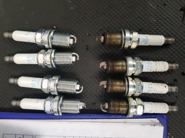 Auction Buy Octavia vRS Estate - Page 2 - Readers' Cars - PistonHeads - The image shows a collection of six spark plugs neatly arranged on a surface, possibly a table or bench. Each spark plug appears to be new and unused, with its metal body and rubber insulator coating the end. They are laid out in two rows of three plugs each, providing a clear view of their design and construction.

The background is a darker surface that contrasts with the shiny chrome of the spark plugs, making them stand out. On the right side of the image, there is a small notebook or clipboard resting against the wall, suggesting an organized workspace. The overall scene implies a setting where these spark plugs might be used for vehicle maintenance or repair, such as a garage or workshop.