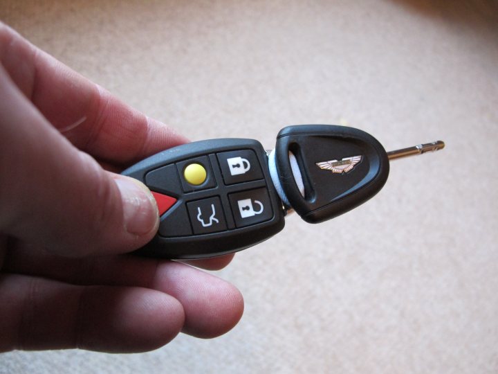 Pistonheads - This image captures a close-up view of a person's hand holding a key remote control. The remote control appears to be for a vehicle, as suggested by the symbol of a car emblem on the upper left side. The remote has various buttons, including a prominent power button, flanked by other buttons on the left. The buttons are likely for different functionalities, such as locking and unlocking, and perhaps for additional features like central locking or alarm activation. The person's fingers are visible, highlighting the interaction between the human and the electronic device.