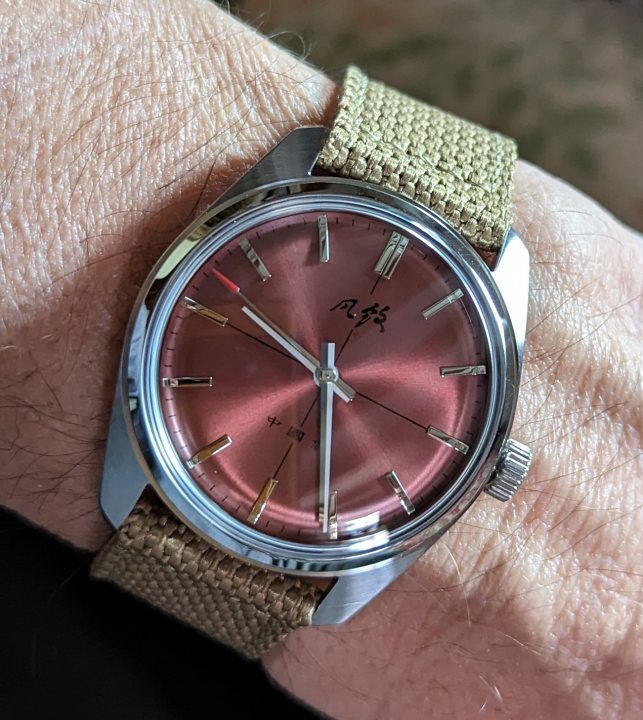 Pistonheads - The image shows a person's wrist, adorned with a watch featuring a distinctive pink dial and black hour markers. The watch is paired with a brown leather strap, adding a touch of elegance to the overall ensemble.