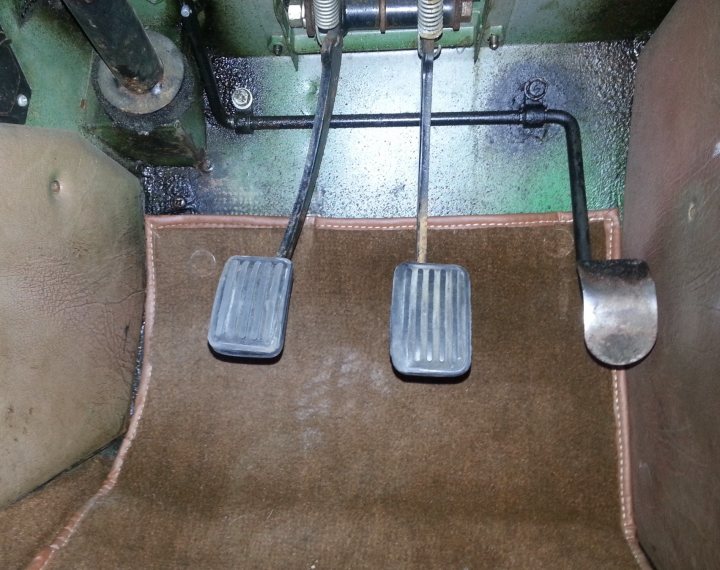 I've still got clutch trouble? - Page 1 - MG - PistonHeads - This image features the pedals and skirt board from the interior of a car, likely in the automatic or manual transmission compartment. There are two metal pedals, one of which has a rubber mat on the side. The carpet beneath the pedals appears worn and may not be in optimal condition. The greenish hue suggests the presence of some fluids, possibly from oil or coolant leaks. The pedals are likely accelerator and brake, essential for driving the vehicle. The environment suggests a possible renovation or repairment in progress.