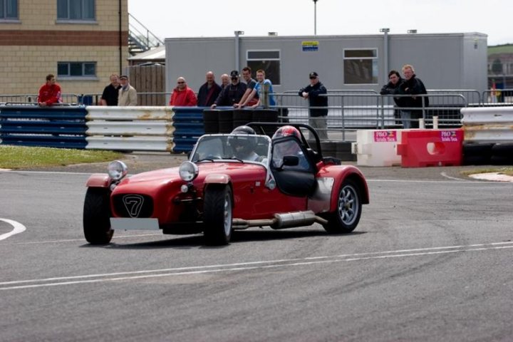 Not enough pictures on this forum - Page 2 - Caterham - PistonHeads - The image portrays an exciting scene from a car race. At the center of the image is a red single-seater race car. This car is detailed, highlighting its speed and performance. It's equipped with a roll bar and is moving around a track.

The atmosphere is charged with thrill and anticipation as the race car maneuvers around a curve. Surrounding the track is a sea of spectators, their figures suggesting a crowd of onlookers.

The fence in the background indicates that the racing venue is a proper stadium or track, designed for such high-speed events. The overall image captures a moment of high drama and edge-of-your-seat excitement inherent in car racing events.