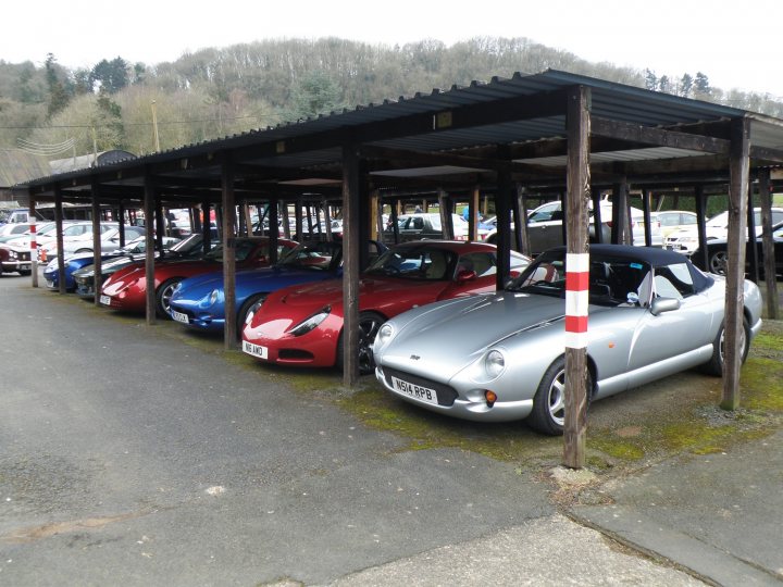 Shelsley Walsh Breakfast Club - Sunday 8th March  - Page 1 - TVR Events & Meetings - PistonHeads - The image captures a quaint street scene where a black and white post stands in front of a group of parked cars and cars under a covered structure. The primary focus is on a silver convertible, which appears to be in motion, creating a vivid contrast with the stationary, vintage convertibles parked next to it. The post serves as a pole with horizontal supports and supports vertical signs for safety or guidance. The cars are various sizes and styles, suggesting that this is a busy, urban area with ample parking facilities. The scene evokes a sense of nostalgia, as the vintage cars offer a glimpse into the past, while the post and covered structure hint at the modern infrastructure in place to accommodate the needs of today.