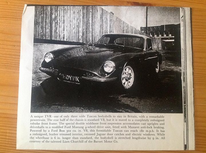 HOY 11K 4wd TVR se restoration project - Page 1 - General TVR Stuff & Gossip - PistonHeads - The image shows a vintage black and white photograph of an older car, prominently featuring its front and hood. The vehicle has a distinct design, with two round headlamps and a grille adorning the front. The car is parked on a street that appears to be in an urban area. In a corner of the image, there's text that likely provides context about the car or the location where the photo was taken. The style of the photo suggests it could be from a past era, possibly from mid-20th century, given the aesthetic and the style of the car.