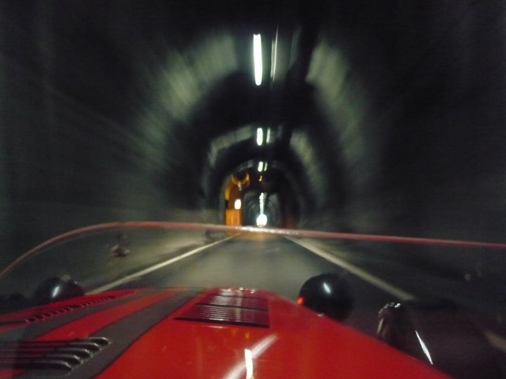 Not enough pictures on this forum - Page 3 - Caterham - PistonHeads - The image captures a thrilling perspective from the cockpit of a speeding red sports car. The scene is a tunnel, the inside of which is curving towards the camera. Blue lights illuminate the tunnel, creating a striking contrast against the dark tunnel walls. It appears that the sports car is moving at high speed, captured by the blurry backdrop. The view suggests the driver is entering the tunnel with great force, enhancing the intensity of the scene.