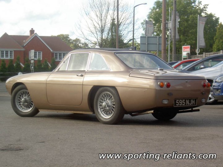 Great British Cars often forgotten - Page 9 - Classic Cars and Yesterday's Heroes - PistonHeads - This image features a unique vehicle parked on the side of a street. It appears to be an old, possibly vintage car with distinctive design elements such as a long body and a large, prominent grille. The vehicle is painted in a shade of brown or gold and has a two-door configuration, with the doors located near the middle. The wheels are covered with wheel covers that have a pattern on them. There's no visible text or branding on the car, which stands out due to its unusual design. In the background, there are other parked cars, buildings, and a clear sky.