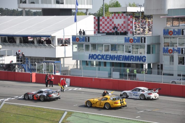 Pistonheads Clark Jim Hockenheimring - The image captures an exciting moment at a car race. Numerous cars are decked out for the race, deeply concentrated into the middle of the lap. Two white banners stand out in the scene, prominently displaying the names "Mobil 11" and "Hockenheimring". The cars are moving fast, setting a high-intensity pace for the race. Spectators can be seen, a testament to the popularity and excitement of the event.