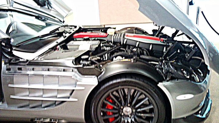 RE: Tell Me I'm Wrong: Mercedes SLR McLaren - Page 4 - General Gassing - PistonHeads - The image showcases the engine of a luxury sports car. The engine's cover is open, revealing a complex array of car parts and a red sensor at the top. The hood of the car is up, providing a clear view of the engine mechanism. The car's design features aerodynamic lines and curves, typical of high-performance sports cars. The engine looks powerful and sophisticated, suggesting that the car is capable of high speeds and performance.