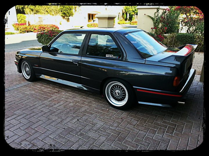 A black and white photo of a classic car - Pistonheads - The image is a color photograph featuring a black sports car parked on a tiled surface. The car is viewed from a rear three-quarter perspective, showcasing its distinctive angular design, large side mirrors, and unique aftermarket exhaust system.

The rear of the car has peculiar aerodynamic modifications that add a touch of individualism, deviating from a standard production vehicle. The license plate is not visible, and the image appears to be taken during daytime with a diffuse background that doesn't provide clear details.

The brakes and suspension components of the car are visible, indicating that the car's wheels are off the ground by approximately two-and-a-half inches, which is necessary to properly admire the focused performance and precise handling of sports cars.

The vehicle is well-maintained and appears to be in excellent condition, with the paint gleaming in the sun and no visible damages or blemishes on the exterior. There is a seat belt wrapped around the passenger seat, suggesting that the car may be unoccupied and parked for display or inspection.