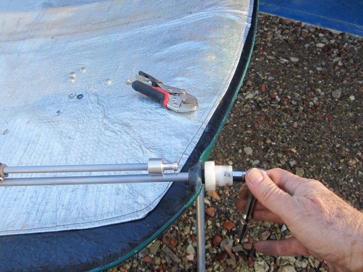 Sneek peak of the new Leven Bonnet stay - Page 1 - Griffith - PistonHeads - The image shows a close-up of a person working on an aluminum surface that appears to be a lawn chair. They are using a wrench to tighten a bolt, which is related to the chair mechanism. The wrench is a specialized tool for turning and torqueing the set bolt that aids in the functionality of the chair. The tiles underneath the surface are visible, showing a garden or outdoor setting.