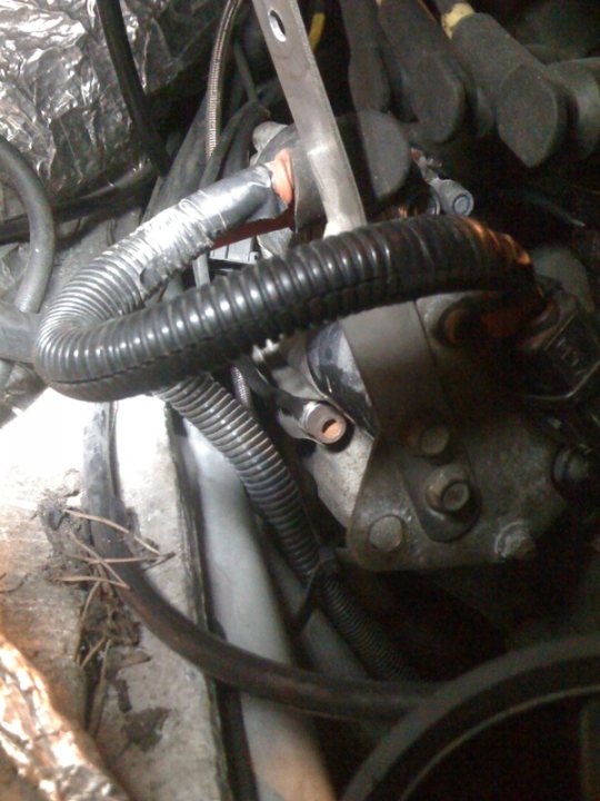 Readings Strange Pistonheads Tpot - This image shows a close-up view of an engine compartment, where several black rubber hoses are intertwined with each other. The hoses are curled up, and have a ladder-like appearance around them. The engine appears to be in the car, given the context of the image. The image is taken from an angle that provides a clear view of the engine components and the hoses. The colors in the image are mostly in shades of black, gray, and rusted metallic parts.