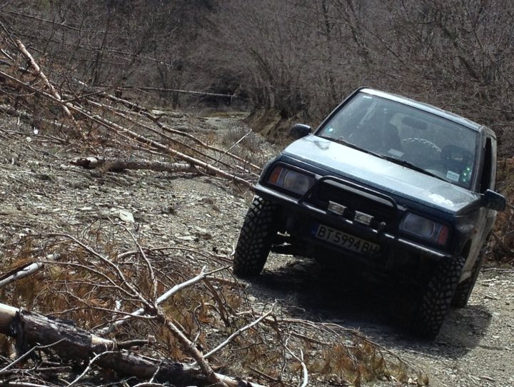 Bit of off-roading, and a bit of camping. - Page 1 - Off Road - PistonHeads - The image shows a rugged rural setting with a sidetrack. A dark-colored off-road vehicle is parked on the edge of this track, next to what appears to be a large fallen tree or a pile of branches. The vehicle's tires suggest it is designed for rough terrain, like dirt roads or uneven surfaces. Behind the vehicle, the terrain is densely covered with brownish crops with rows running parallel to each other. The sky above is blue, indicating a clear day. The photo gives the impression of a day trip or outdoor adventure in a rural area.