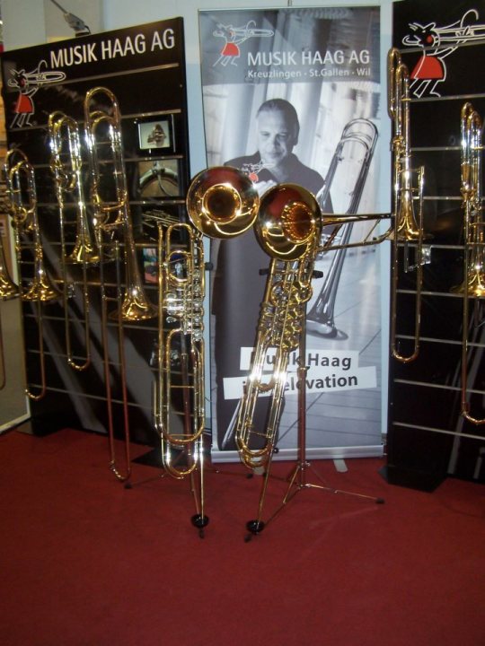 A bunch of different colored vases on display - The image showcases a display of brass instruments in what appears to be a showroom or store setting. The instruments include a variety of trumpets and trombones, each with its own unique features. These instruments are identified as "Music Haag AG," a company known for its wind instruments, through the visible branding on each brass instrument. The surrounding walls have promotional displays for the brand's products, accompanied by imagery and text related to the companies offerings and services.