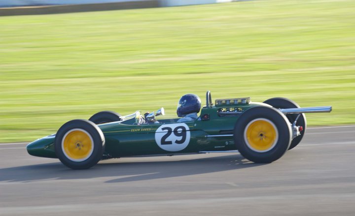 2012 Goodwood Revival Meeting Photo Gallery - Page 1 - Goodwood Events - PistonHeads - The image displays a vintage race car in motion on a race track, evident from the blurred rear tires. The car is predominantly green with yellow rims, featuring a numerical "29" prominently on its side. At the rear of the vehicle, a driver wearing a helmet is visible, adding to the dynamic nature of the photo. The setting suggests a clear day with lush green grass forming the backdrop of this historic race car in action.