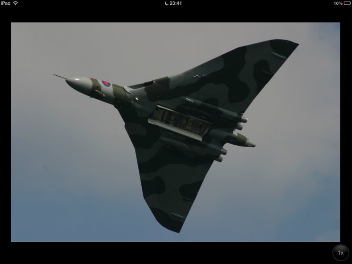 Wings & Wheels 24th & 24rth Dunsfold - Page 1 - Thames Valley & Surrey - PistonHeads - This is an image of an airplane captured in mid-flight. The airplane is predominantly grey and features a camouflage pattern, suggesting it might be a military or special forces aircraft. Based on the image's metadata, the photo is taken from the ground and is taken during the time 16:09:50, which could suggest that it is 4:09 PM. The sky forms a backdrop that contrasts with the camouflaged pattern of the aircraft.