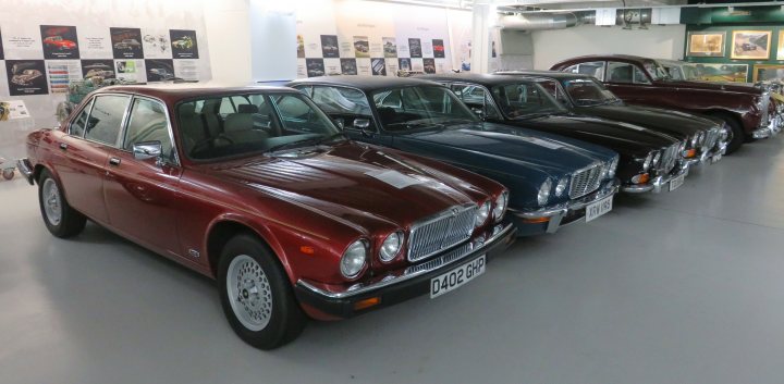 Pistonheads - This image features a collection of classic cars displayed in a well-lit indoor area. There are three cars parked side by side, each exhibiting different colors and models. The first car is red, the second is blue, and the third has a gold or brown hue, possibly with some white trim. The setting appears to be a car show or museum, as suggested by the polished floor and the calm atmosphere. In the background, there are what seem to be plaques or information panels, indicating that this is an organized exhibition meant for viewers to appreciate the design and history of these vehicles.