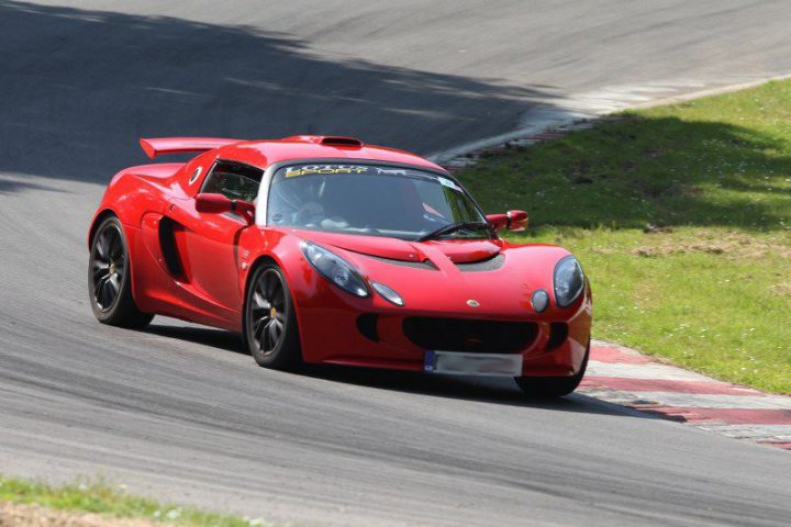 A red car with a surfboard on top of it - Pistonheads - In the image, a red Nissan GT-R sports car is captured in motion on a curvy racetrack, leaning onto its side. The car is positioned in the lower right corner of the frame as it navigates the curves, showcasing agility and speed. The vibrant red color of the car is contrasted by the green of the grass and the black of the track. The image depicts an exhilarating moment of speed and control, with the sports car clearly the focal point against the dynamic backdrop.