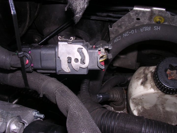 Pistonheads - The image depicts the underside of a car engine, with the focus on a mechanical part that appears to be damaged or in need of repair. There is a gas line running along the engine's base, which is covered in a dark, possibly dirty substance. A black and gray hose is also visible, and there are yellow papers or labels with markings on them, possibly indicating specific components or points of interest. The overall scene looks like a vehicle that has been the subject of an inspection or maintenance process.