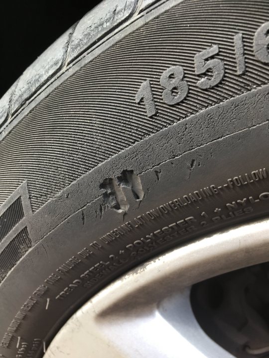 The ask an MOT tester thread - Page 113 - General Gassing - PistonHeads UK - The image shows a close-up view of a tire on a vehicle. The tire has a label with the text "185 R16 35 95 72" indicating its specifications and size. There is visible damage on the sidewall of the tire, which suggests it has been punctured or run over. The tire appears to be an older model with a somewhat worn appearance. The background of the image is dark and indistinct, focusing the viewer's attention on the damaged tire.