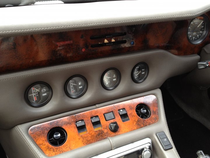 TVR23 V8S Body Off Restoration - Page 1 - S Series - PistonHeads - The image shows the center console of a car with a close-up view of its control panel. The panel is adorned with an array of buttons and knobs, indicating various functions and controls. The design suggests a combination of modern functionality with a classic aesthetic, as indicated by the presence of dials and the color gradient on the panel. The panel exhibits signs of wear, with scratches and marks adding character to the otherwise sleek and smooth surface. There are no texts present, focusing the viewer's attention on the physical elements of the car's control system.