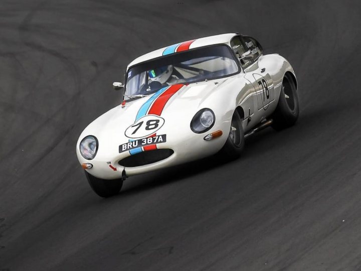 A large white and black motorcycle on a road - Pistonheads - The image shows a vintage racing car in motion on a track. The car is predominantly white with red and blue stripes running down its side. It has a large rear wing, suggesting it's designed for high-speed aerodynamics. The vehicle is numbered 87 and appears to be participating in a race, as indicated by the race number and the presence of racing equipment on the car. The background is blurred, emphasizing the speed and movement of the car, while the track itself has visible tire marks. There's also text overlaying the image, but it's not clear enough to read accurately.