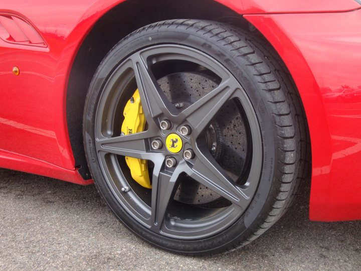 Oxford Service Sunday Pistonheads - The image showcases the wheel of a red vehicle, possibly a sports car, positioned in a closer shot. The color of the wheel is a striking contrast of black, which stands out against the red body of the car. The rims of the wheel are painted in a vibrant yellow, adding another pop of color to the car's appearance. This rear wheel's design is sleek and modern, with a five-spoke configuration enhancing the overall aesthetic of the vehicle. The car's red color and sporty styling suggest a performance-oriented vehicle.