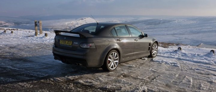 My VXR8 - pics taken today - Page 1 - Readers' Cars - PistonHeads - This image captures a scene of a single, dark-colored car parked on a snowy road. The car is sleek and modern, with a distinctive design element: a towering above the rear at an angle, suggesting that the car is equipped for handling challenging weather conditions. The car is surrounded by a landscape blanketed in white snow, with hills or mountains in the distance under a cloudy sky. The setting appears to be a remote area during winter, as evidenced by the lack of other vehicles or buildings nearby. The overall tone of the image is quiet and still, conveying a sense of solitude in the midst of a harsh but beautiful winter landscape.