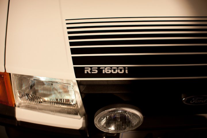 Pistonheads - This image features the headlight of a white truck. The headlight has a clear and clean appearance, indicating it's in good condition. Below the headlight, there's an emblem with text "RS 1600I," suggesting it's a vehicle associated with the F-150 Raptor line, which is a high-performance truck manufactured by Ford. This emblem is prominently displayed on the front of the vehicle. The overall style of the image is a close-up, with the focus being on the determining factors of the vehicle's brand and make. The photograph captures the attention of the vehicle's distinctive design elements.