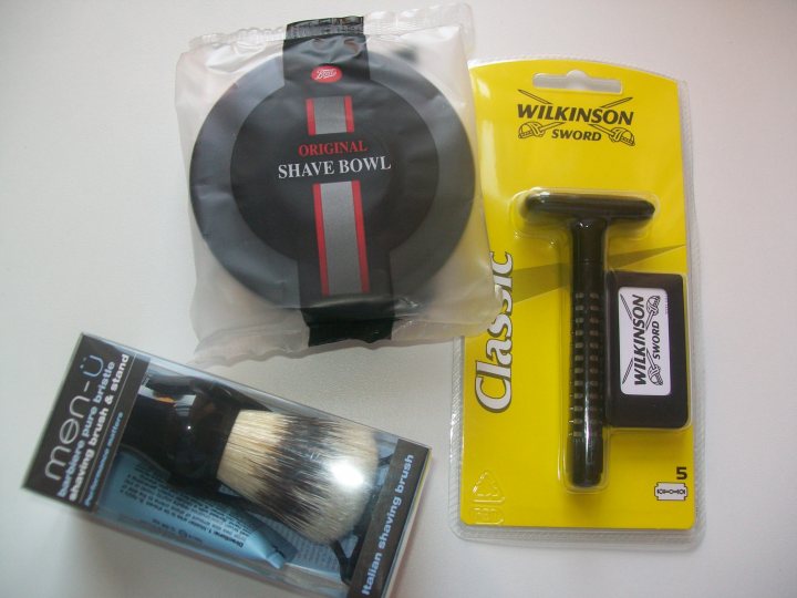 Multiblade Pistonheads Razors - The image presents a set of shave and grooming items laid out neatly on a surface. There's a black shave bowl that matches with the black handle of a Wilkinson Sword Classic Razor. Next to the razor, there's a package of hair clippers, suggesting the set is designed for both shaving and styling hair. Lastly, a black brush is visible amongst the other items, likely included for post-shave grooming. The branding is notable, with "Classic" and "Wilkinson Sword" prominently displayed on the packaging and handle of the razor. Overall, the arrangement hints at a comprehensive grooming routine that incorporates shaving, hair styling, and overall hair care.