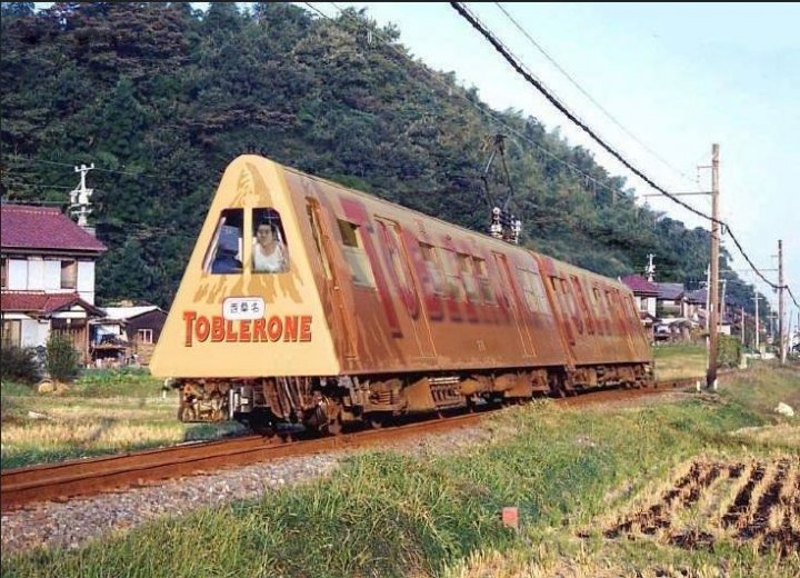 A train traveling down tracks next to a forest