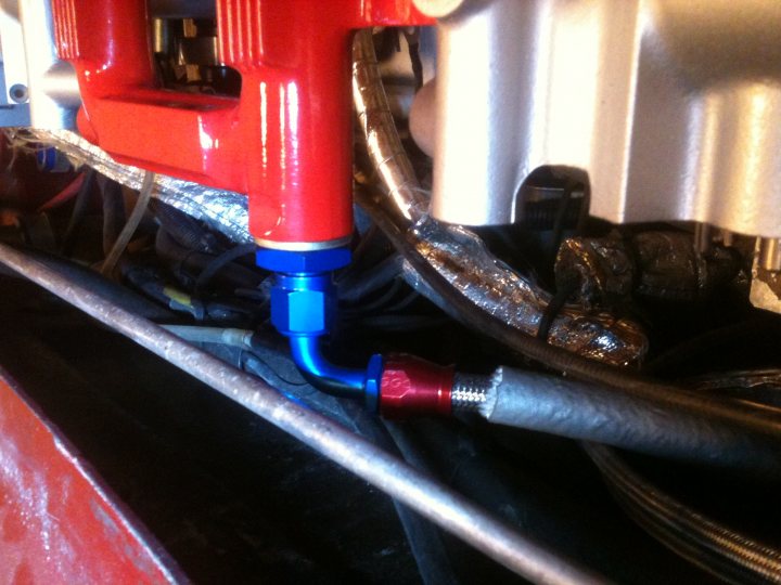 Leaking fuel pipe - Page 1 - Cerbera - PistonHeads - The image presents a close-up view of the underside of a vehicle, focusing on a bunch of brake lines. The brake line, a silver hose, is encased by a red hose that connects to the brake line. A blue valve is mounted to the red hose, adding a splash of color to the scene. On the other end, there's an engine control unit, a crucial component in modern vehicles. The complexity of the hoses suggests that this is not a casual glace at a car; it's a detailed look into the vehicle's crucial systems.