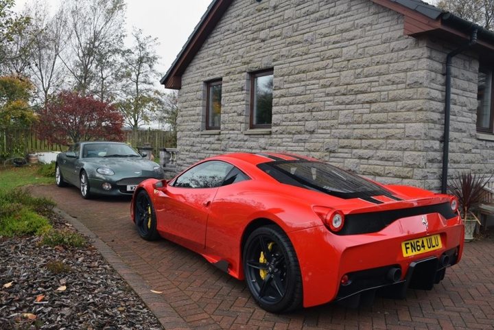 Speciale arrived today - Page 1 - Ferrari V8 - PistonHeads - The image shows a scene outside a house. There are two cars parked in the driveway. On the left, there is a sports car, which appears to be a convertible, that is red in color. On the right, there is a classic car in a classic gray color. The house itself is constructed of stone or brick, and there are mature trees visible in the background. The driveway seems to be well-maintained, and it appears to be a residential area.