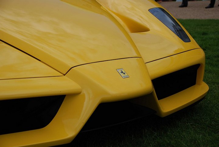 GRRC Lunch Club - Page 1 - Goodwood Events - PistonHeads - The image features a vibrant yellow car parked on grass, angled slightly away from the camera. The front of the car is prominently visible, showcasing the car's characteristic large air intakes and the Ferrari emblem. The design is reminiscent of high-performance sportscars, suggesting it may be a racing car. In the background, there are more cars visible, slightly obscured by the close-up of the yellow car.