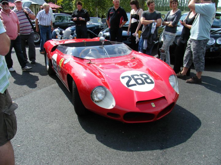 Breakfast Meeting, The Hare, Roxwell 4th June - Page 1 - Kent & Essex - PistonHeads - The image showcases a red Ferrari race car from 1968, exhibited at a car show. The car is positioned in front of an asphalt tent with spectators on either side, gathered around to appreciate its vintage charm. The event appears to be a public gathering where enthusiasts can view and discuss classic and race cars.